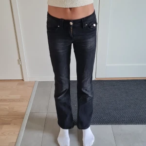 Svarta bootcut jeans Gina Tricot - Snygga svarta jeans från Gina Tricot i storlek 158. Modellen har bootcut-ben, klassiska fem fickor och silverfärgade knappar. Jeansen har låg midja och ser korta ut på mig eftersom jag är 170 cm lång.