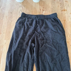 Svarta wide mjukisbyxor med snörning - Svarta linnebyxor med breda ben och skön passform. De har elastisk midja med snörning och är gjorda i mjukt bomullsmaterial. Perfekta för chill dagar eller när du vill ha det extra bekvämt. Snyggt loose fit/bootcut och klassisk svart färg. Storlek XS xtra tall, innerben 85 midja: 34 men väldigt stretchig! gren: 21