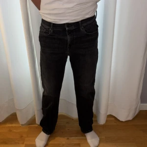 Svarta jeans från Replay straight fit - Säljer ett par svarta jeans från Replay med klassisk femficksdesign och raka ben. Jeansen har en mörk tvätt och detaljer vid fickorna. Passformen är straight och materialet är slitstarkt denim. Storlek 158cm (14 år)