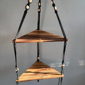 Hängande hylla med ”snören” - En hängande hylla i trä med svarta snören och träpärlor. Den är som ny! 