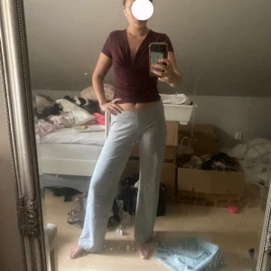 Vinröd omlottopp med v-ringning - Säljer en vinröd omlottopp  i stretchigt och mjukt material. Toppen har korta ärmar, v-ringad hals och snygga draperingar framtill som ger en cool look. Perfekt att styla med jeans eller kjol för en trendig vibe.