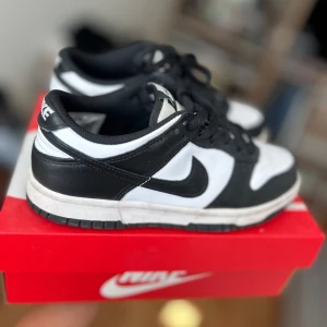 Nike Dunk Low svart/vit sneakers - Nike Dunk Low sneakers i svart och vitt. Ovandel i skinn och textil, slitstark gummisula. Perfekt för dig som gillar clean och tidlös streetstil. 