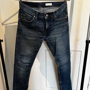 Mörkblå slim jeans Tiger of Sweden - Snygga mörkblå slimfit jeans från Tiger of Sweden med klassisk femficksdesign och diskreta slitningar. Jeansen har smal passform och är tillverkade i stretchigt denim. Modellen är Pistolero.