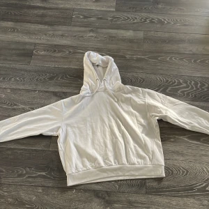 Vit hoodie från 157, storlek M - Säljer en clean vit hoodie från 157 i storlek M. Tröjan har huva med snörning och långa ärmar, samt bred mudd vid midjan. Perfekt för chill dagar eller när du vill ha en enkel och snygg look. Materialet är mjukt och känns skönt mot huden.