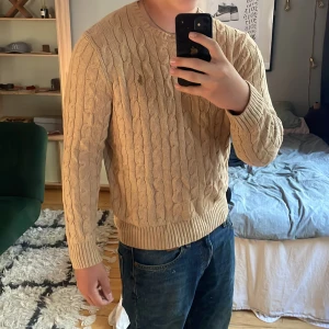  tröja me mönster Polo Ralph Lauren  - Säljer en tröja från Polo Ralph Lauren i storlek M. Tröjan har rund hals, ribbade muddar och ett diskret broderat logomärke på bröstet. Perfekt för dig som gillar klassisk stil med snygga detaljer.