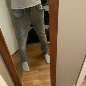 Grå slim fit jeans - Säljer ett par grå slim fit jeans från Jack & Jones i modellen Glenn. De har en snygg, sliten look med snygga slitningar. Personen på bilden är och 177 väger 62