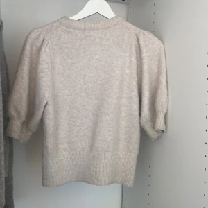 Beige stickad tröja från H&M - Säljer en beige stickad tröja från H&M i storlek S. Tröjan har puffade korta armar. Säljer för 90kr. Ursprungspris 299kr.