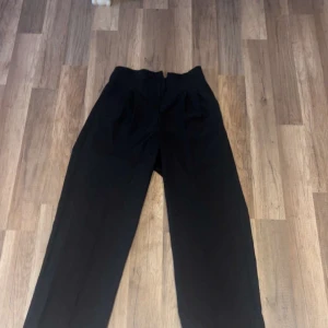 Svarta wide kostymbyxor från DAZY - Säljer ett par svarta kostymbyxor från DAZY i storlek M. Byxorna har en hög midja och ett wide snitt som ger en chill och modern vibe. Perfekta att styla med sneakers eller boots. Materialet känns mjukt och har en snygg fall.