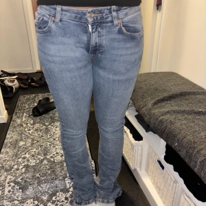 Ginatricot lowwaist ljusblå jeans bootcut  - Snygga ljusblå ginatricot jeans med klassisk femficksdesign och bootcut-ben. Jeansen har låg midja och är gjorda i mjukt denim med dragkedja och knapp framtill. Perfekta för dig som gillar en avslappnad men ändå stilren look. Omsydda till low waist så lite fula på insidan, ett hål pga att jag drog byxorna för hårt. Passat jättebra på mig som brukar ha storlek 36 då de är stretchiga.