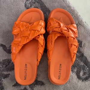 Flätade orange sandaler från Nelly - Sandaler från Nelly med breda, flätade remmar och platt sula. Står både 38 och 39 i skon men jag har köpt de i storlek 38 och är normalt en 37-38 så skulle gissa att de inte funkar på någon med storlek 39. Ordinariepris: 399kr