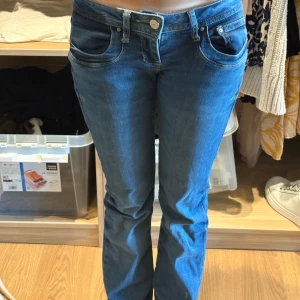 Blå bootcut jeans från LTB - Snygga blå jeans från LTB med bootcut passform och låg midja. Klassisk femficksdesign och coola detaljer vid fickorna. Jeansen har en mörkblå ton och är tillverkade i mjukt denim-material som sitter skönt. Lite större i storleken men passar mig som har oftast storlek w24 L32. Jeansen är i storlek W25 L32.