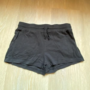 Svarta shorts med snörning - Svarta mjuka shorts med snörning i midjan och fickor på sidorna och elastisk midja.