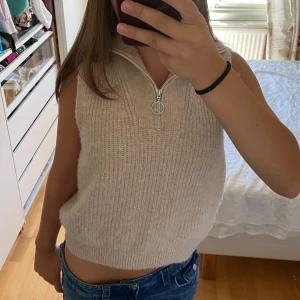 Beige stickad väst från Lindex - Mysig beige stickad väst från Lindex med ribbad struktur och half zip-dragkedja framtill.