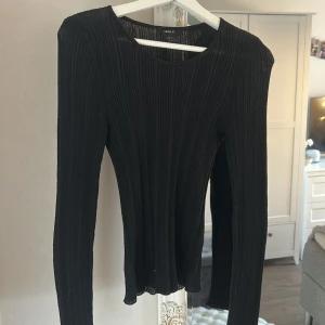 Svart ribbad långärmad tröja Lindex - Snygg svart långärmad tröja från Lindex i storlek S. Tröjan har ett ribbat tyg med vertikala ränder som ger en cool struktur och sitter skönt mot kroppen. Rund halsringning och stretchigt material som passar perfekt till jeans eller kjol.
