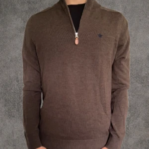 Brun merinoullströja med half zip Morris - Snygg brun långärmad tröja från Morris i 100% merinoull. Modellen har en stilren half zip framtill och ribbade muddar vid ärmslut och nederkant. Perfekt för dig som gillar klassisk stil med en modern touch. Diskret Morris-logga på bröstet.