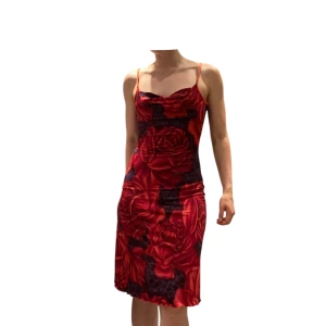 Röd blommig kortklänning med paljetter - Röd kort klänning med stora rosor. Klänningen har justerbara smala axelband, paljetter som glittrar och en draperad halsringning (cow neck). Stretchigt material. Stork uppskattas till s/m