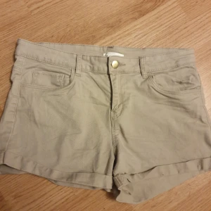 Shorts från hm - Snygga beige shorts med klassisk femficksdesign och uppvikta benslut. De har en guldig knapp framtill och hällor för bälte. Materialet är mjuk bomull som känns skönt mot huden. Perfekta för varma dagar och enkel att matcha med din favorit-t-shirt. Använda 1 gång. Storlek 38