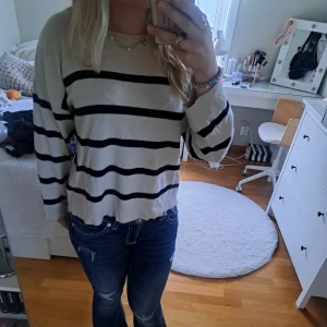 Randig beige tröja från Neo Noir - Säljer en beige tröja från Neo Noir med svarta horisontella ränder. Tröjan har en loose passform, rund hals och långa ärmar. Materialet är mjukt och känns som bomull eller syntet. Perfekt för chill dagar och enkel att styla med jeans eller kjol.