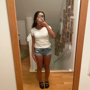 Vit t-shirt från Polo Ralph Lauren - Vit t-shirt från Polo Ralph Lauren. T-shirten har en marinblå broderad logga på bröstet och är gjord i mjuk bomull. Passformen är slim och modellen är enkel och stilren, perfekt till jeans eller shorts.