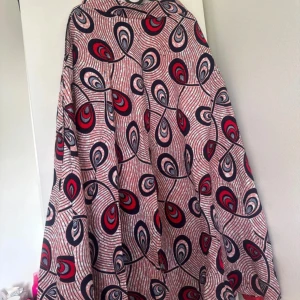 Lång skirt med röd och blå mönster - Säljer en maxiskirt med unikt mönster i rött, blått och vitt. Klänningen har ett svepande fall och är täckt av ett grafiskt, nästan psykedeliskt mönster med droppformade detaljer. Perfekt för dig som vill sticka ut med färg och cool design.