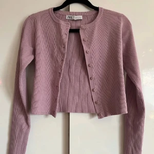 Ribbad ljuslila kofta - En ljuslila ribbad kofta från Zara i strl S. Den har rund hals, långa ärmar och knappar hela vägen nedframtill. Koftan är lite croppad i modellen!💞