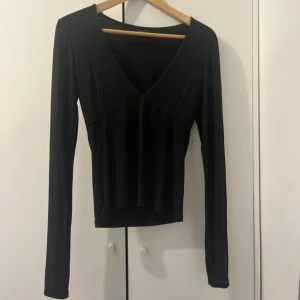 Svart v-ringad topp Gina Tricot - Svart långärmad topp från Gina Tricot med snygg v-ringning och figurnära passform. Enkel och stilren design som funkar till många olika looks. Mjuk och stretchig bomullskänsla, perfekt att matcha jeans eller kjol. Pris kan diskuteras💕