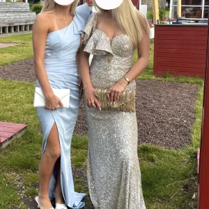 Champagne glittrig balklänning!! - Säljer en superfin balklänning i champagne/ silver med glittriga paljetter. Klänningen har en axel, volangdetalj över bysten och figurnära passform. Använd en gång och i fint skick! Skriv vid frågor🤩