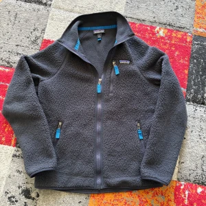 Marinblå fleecejacka från Patagonia S - Mysig marinblå fleecejacka från Patagonia i storlek S. Jackan har hel dragkedja, tre fickor med blå detaljer och hög krage. Perfekt för kyliga dagar och outdoor vibes. Materialet är mjuk fleece som håller dig varm och bekväm. (Kvitto finns)
