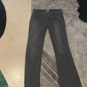 Grå bootcut jeans från 157 - Snygga grå jeans från 157 med bootcut passform och raka ben. Byxorna har stora framfickor, klassiska bakfickor och dubbla knappar i midjan. Perfekta för dig som gillar en avslappnad men trendig stil.