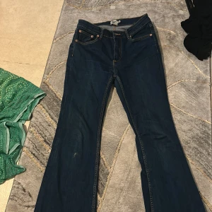 Mörkblå bootcut jeans från 157 - Snygga mörkblå jeans från 157 med klassisk bootcut-modell och kontrastsömmar. Jeansen har fem fickor, normal passform och är tillverkade i ett mjukt denimtyg. Perfekta för dig som gillar retrovibbar och vill ha ett par jeans med lite vidare ben.