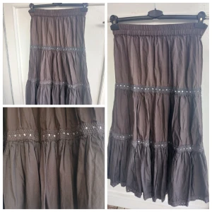 Brun volangkjol med paljettdetaljer stl 34  - Säljer en brun långkjol i bomull med flera volanger och elastisk midja. Kjolen har dekorativa band med små paljetter som ger lite extra bling. Perfekt för dig som gillar boho-vibes och vill ha något flowy och bekvämt.