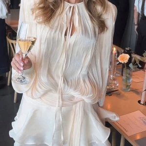 Miss Rosier Klänning! - Jättevacker klänning från Miss Rosier. Använd 1 gång, precis som ny! Säljer pga lite för kort för mig. Har använt som topp också (se bild 2).  Namn: Eugénie Neutral Fully Pleated Ruffled Mini Dress Material: 88% Terylene fiber, 10% Viscose, 2% Spandex