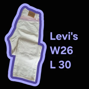 Vita Levi's Premium jeans W26 L30 - Snygga vita Levi's Premium jeans med rosa och lila ränder baktill vid linningen. Klassisk femficksmodell i bomull med raka ben och läderpatch bak. Perfekta för dig som vill sticka ut med en unik detalj på dina jeans. Tillhör deras pride kollektion.