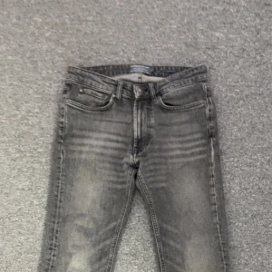 Grå jeans med råa kanter / gray jeans with flared bottoms  - Snygga grå jeans med slitna detaljer och råa, fransiga benslut. Jeansen har klassisk femficksdesign och dragkedjegylf. Perfekta för en avslappnad och trendig look.