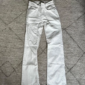 Vita jeans från Gina tricot - Snygga vita jeans från Gina Tricot jeans i storlek 36. Modellen har hög midja och raka ben med klassisk femficksdesign. Jeansen är tillverkade i ett stadigt bomullstyg och har silverfärgade nitar och knapp framtill.