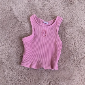 Rosa ribbad linnetopp från Zara - Supersöt rosa ribbad linnetopp från Zara med ett unikt utskuret motiv framtill. Toppen är ärmlös och har en croppad passform som känns både trendig och lekfull. Perfekt för dig som gillar färg och detaljer som sticker ut.