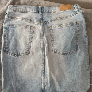 Ljusblå jeanskjol med fransig kant - Säljer en ljusblå jeanskjol från 157 med fransig nederkant och klassiska fickor både fram och bak. Kjolen har knappar framtill och bälteshällor i midjan. Perfekt för dig som gillar en avslappnad och trendig stil.