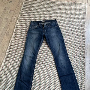 Mörkblå bootcut jeans från Lee - Snygga mörkblå jeans från Lee med klassisk femficksdesign och bootcut-ben. Jeansen har en lätt tvättad look och är tillverkade i slitstarkt denim. Perfekta för dig som gillar en tidlös och avslappnad stil.