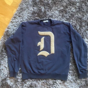 Mörkblå sweatshirt från Dondup - Snygg mörkblå sweatshirt från Dondup med ett stort, beige broderat D på bröstet. Mycket bra skick. Storlek S. Hör av er vid intresse!!