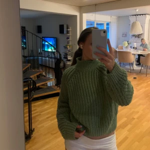 Grön stickad polotröja - Mysig grön stickad polotröja med grov struktur och höga muddar. Tröjan har en hög krage och en loose fit som ger en chill vibe. Perfekt att slänga på sig när det är kallt ute.