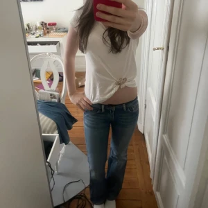 Blå bootcut jeans låg midja - Säljer ett par klassiska blå jeans med bootcut och låg midja. Jeansen har fem fickor, snygga slitningar och en lätt tvättad look. Perfekta till sneakers eller boots och ger en avslappnad vibe. Materialet är jeans med lite stretch för extra komfort.