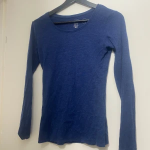 Blå långärmad tight tröja H&M - Mörkblå långärmad tröja från H&M L.O.G.G. i tight fit. Tillverkad i mjuk ekologisk bomull, med rund halsringning och enkel, stilren design. Perfekt att styla med jeans eller kjol för en clean look.