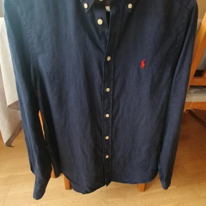 Mörkblå skjorta från Polo Ralph Lauren - mörkblå skjorta från Polo Ralph Lauren i linne perfekt för sommaren. Sälj pga blivit för liten. Storlek l barn men passar xs. Pris 499 inte huget i sten.