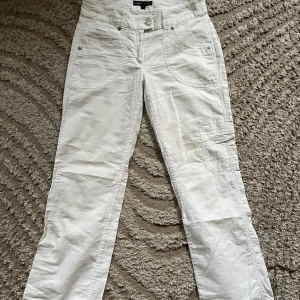 Vita cargopants från Lindex - Snygga vita cargopants från Lindex med låg midja och raka ben. Byxorna har flera fickor, bland annat på sidorna och bak med knappdetaljer. Obs en knapp fattas. Perfekta för en avslappnad och trendig stil. Midja: 41 innerben: 83