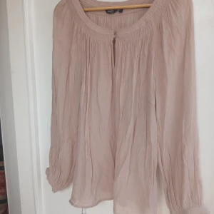 Söt blus lindex stl L  - Somrig söt blus i ljus beige färg med knapp framtill o snörning nertill så man kan välja om man vill ha den tajt eller lite lösare.  Fint skick o hittar inget att anmärka på. Stl L 