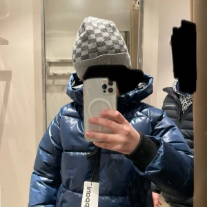 Blå pufferjacka från Kappahl, stl 146 - Snygg blå pufferjacka från Kappahl i storlek 146. Jackan har glansig finish, huva och dragkedja framtill. Perfekt för kalla dagar med sin vadderade look och ribbade muddar vid ärmsluten. Enkel och stilren design som håller dig varm.den är använd ungefär 10 gånger