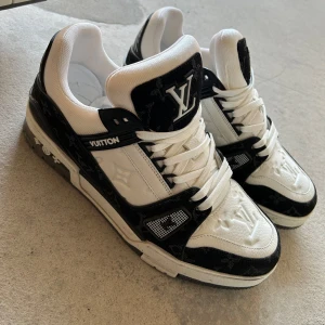 Louis Vuitton svartvita sneakers - Exklusiva Louis Vuitton sneakers i svart och vitt skinn med tydliga LV-loggor på plös och tå. Snygga detaljer i svart med diskret mönster och vita snören. Klassisk rund tå och platt sula. Kommer med originalkartong, dustbags och kvitto. Använda två gånger. 