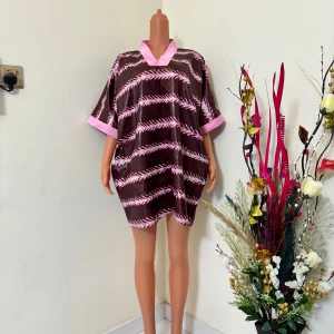  Rosa kortklänning med mönster - Snygg kortklänning i  rosa detaljer och grafiskt mönster. Klänningen har lös passform, korta ärmar och V-ringad hals med rosa kant. Perfekt för dig som gillar färg och vill sticka ut med en unik look.