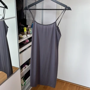 Grå ärmlös klänning med smala band - Enkel och stilren grå klänning med smala axelband och rak passform. Klänningen är ärmlös och har en mjuk, slät yta som känns skön mot huden. Köpt från shein därav billigt pris. DMa för mer info🩷