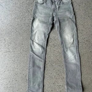 Grå Nudie jeans - Ett par grå Nudie jeans med ljusgrå slitning. Bekväma och hållbara jeans. Jeans modellen är Skinny Lin med färgen gray croy i storleken W29 L34. Bara att skriva vida minsta lilla fundering!